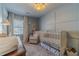 Serene Bedroom with a crib, glider, stylish wall paneling, and soft, neutral colors for a peaceful atmosphere at 1953 Graystone Pkwy, Grayson, GA 30017