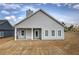 A gray home showcasing a covered porch, white trim windows, and a spacious backyard covered in newly laid sod at 203 Daisy Ne Ct, Cartersville, GA 30121