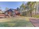 Wide backyard view of a brick two-story home with a deck and screened porch overlooking the lawn at 5020 Puritan Dr, Sugar Hill, GA 30518