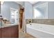 Bright bathroom with a soaking tub, tiled shower, and wood vanity with granite countertop at 9204 Malcolm Dr, Covington, GA 30014