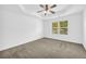 Large bedroom with a tray ceiling, ceiling fan, large window, and neutral carpeting at 11961 Lovejoy Crossing Way, Hampton, GA 30228