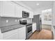 Modern kitchen featuring stainless steel appliances, granite countertops, and white cabinetry at 11961 Lovejoy Crossing Way, Hampton, GA 30228