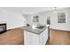 Open living space with a kitchen island, fireplace, and wood floors at 11961 Lovejoy Crossing Way, Hampton, GA 30228