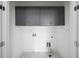 Laundry room featuring gray upper cabinets, white walls, and hexagon tile flooring at 185 Bellehaven Dr, Woodstock, GA 30188