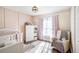 Cozy bedroom featuring decorative wall paneling, window with curtains, a crib, and a comfortable chair at 7760 Poppy Dr, Winston, GA 30187