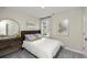 Bright bedroom with a brown leather headboard, white linens, stylish grey and gold artwork and a round mirror at 1216 Arnhem Dr, Hampton, GA 30228