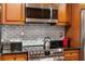 Close-up of stainless steel oven, cooktop, and microwave with stylish tile backsplash in updated kitchen at 3203 Lenox Ne Rd # 1, Atlanta, GA 30324