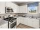 Well-lit kitchen featuring white cabinets, granite countertops, and stainless steel appliances at 1220 Arnhem Dr, Hampton, GA 30228