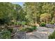 Secluded stone patio with a table and chairs overlooking the landscaped backyard and wooded scenery at 3814 Vermont Ne Rd, Atlanta, GA 30319