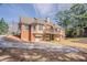 Backyard view of a two-story brick home featuring a back deck, garage, and driveway at 1621 Annapolis Way, Grayson, GA 30017