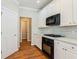 Functional kitchen featuring white cabinets, a gas cooktop, and black appliances, on rich hardwood floors at 1621 Annapolis Way, Grayson, GA 30017