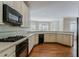 Well-equipped kitchen with black appliances, tiled backsplash, white cabinets, and hardwood floors at 1621 Annapolis Way, Grayson, GA 30017