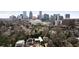 Aerial view of a modern home nestled among trees with the city skyline in the background at 79 Beverly Ne Rd, Atlanta, GA 30309