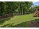 Spacious backyard featuring a manicured lawn, metal fencing, mature trees, and access steps to deck above at 403 Glenhurst Trce, Canton, GA 30115