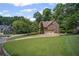 View of a brick two-story home with mature trees and a long driveway leading to a two-car garage at 403 Glenhurst Trce, Canton, GA 30115