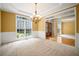 A sun-lit room with carpet, wainscoting, a chandelier, and a view of the home's front entrance at 403 Glenhurst Trce, Canton, GA 30115