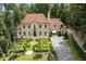 Stunning stone home with manicured lawn, fountain, and porte-cochère entrance, surrounded by lush trees at 4975 Rebel Trl, Atlanta, GA 30327