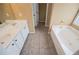 Bright main bathroom with double sinks, vanity, soaking tub, tile floors, and gold hardware at 2657 Neighborhood S Walk, Villa Rica, GA 30180