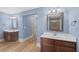 Bathroom featuring dual vanities, wood floors, and decorative mirrors at 825 Bufflehead Ct, Stockbridge, GA 30281