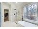 Bright bathroom featuring a large tub, window, walk-in shower, and walk-in closet at 6641 Poplar Grove Way, Stone Mountain, GA 30087