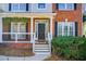 Charming home entrance featuring a black door with sidelights, brick facade, and inviting porch with hanging plants at 6641 Poplar Grove Way, Stone Mountain, GA 30087
