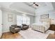 Bright main bedroom with tray ceiling, ceiling fan, two chairs, and a decorative rug at 6641 Poplar Grove Way, Stone Mountain, GA 30087