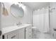 Clean bathroom showcasing a modern vanity with a round mirror and a shower with white tile and shower curtain at 135 Cowan Trl, Stockbridge, GA 30281