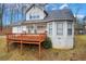Exterior view of a cozy home with a deck and a sloping yard with mature trees in the background at 135 Cowan Trl, Stockbridge, GA 30281