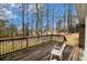 View of the back deck with chairs, wooden railing, and a view of the wooded backyard at 405 Putting Green Ln, Roswell, GA 30076