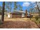 View of the brick house, a wooden deck, a two-car garage, and a tree-covered backyard at 405 Putting Green Ln, Roswell, GA 30076