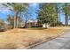 Brick house with a columned front porch on a tree-lined lot, showcasing its serene setting at 405 Putting Green Ln, Roswell, GA 30076