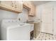A well-lit laundry room featuring a washer, dryer, and upper cabinets at 606 Wedgewood Dr, Woodstock, GA 30189