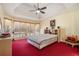 Bright main bedroom with tray ceiling, large windows, and plush red carpeting at 606 Wedgewood Dr, Woodstock, GA 30189