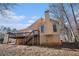 Tan two-story home featuring a large wooden deck with a staircase, complemented by a chimney and rounded windows at 606 Wedgewood Dr, Woodstock, GA 30189