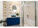 Modern bathroom with a unique gold and white wallpaper, a stylish blue vanity, and a glass-enclosed shower/tub combination at 791 Wylie Se St # 105, Atlanta, GA 30316