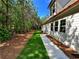 Landscaped backyard features a grassy yard, concrete walkway, and view of the lush green forest at 136 Rainey Rd, Temple, GA 30179
