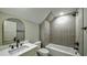 Bathroom with white vanity, arched mirror, and tiled tub and shower at 136 Rainey Rd, Temple, GA 30179