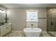 Bathroom showcasing marble floors, soaking tub, modern vanity and fixtures, and large window with natural light at 136 Rainey Rd, Temple, GA 30179