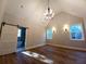 Bedroom showcasing wood floors, vaulted ceilings, elegant chandelier, and a sliding barn door to the ensuite bathroom at 136 Rainey Rd, Temple, GA 30179
