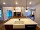 Kitchen island with a white farmhouse sink, dark cabinetry, and view to living area with stone fireplace at 136 Rainey Rd, Temple, GA 30179
