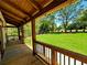 Covered porch offers a relaxing outdoor space with wood flooring, railing, and a lush green lawn view at 136 Rainey Rd, Temple, GA 30179