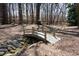 Charming backyard landscape with a decorative bridge over a rock-lined stream, creating a tranquil retreat at 2000 Stethem Ferry Rd, Johns Creek, GA 30022