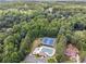 Aerial view of the community pool and tennis courts surrounded by mature trees in a lush neighborhood at 7115 Doncaster Ct, Cumming, GA 30040