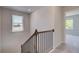 Upstairs hallway with railing leading to carpeted bedrooms and natural light from the window at 132 Dalston Cv, Stockbridge, GA 30281