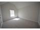 A bright bedroom featuring neutral carpeting and a vaulted ceiling, illuminated by natural light from the window at 2417 Overlook Ave, Lithonia, GA 30058
