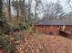 Back of a brick home with a wooden deck, a few windows, and a wooded lot surrounded by trees and foliage at 1900 Calloway Nw Dr, Atlanta, GA 30314