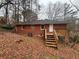 Rear exterior view of a brick home with a wooden deck, backyard stairs and a wooded lot at 1900 Calloway Nw Dr, Atlanta, GA 30314