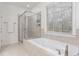 An elegant bathtub featuring a glass-enclosed shower, ceramic tile and bright natural light from the window at 2363 Palladian Manor Se Way # 4, Atlanta, GA 30339