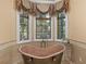 Relaxing bathroom highlighting a copper tub, natural light, and elegant window coverings at 2554 Emerald Dr, Jonesboro, GA 30236