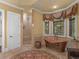 Elegant bathroom featuring a copper tub, tiled shower, and decorative window treatments at 2554 Emerald Dr, Jonesboro, GA 30236